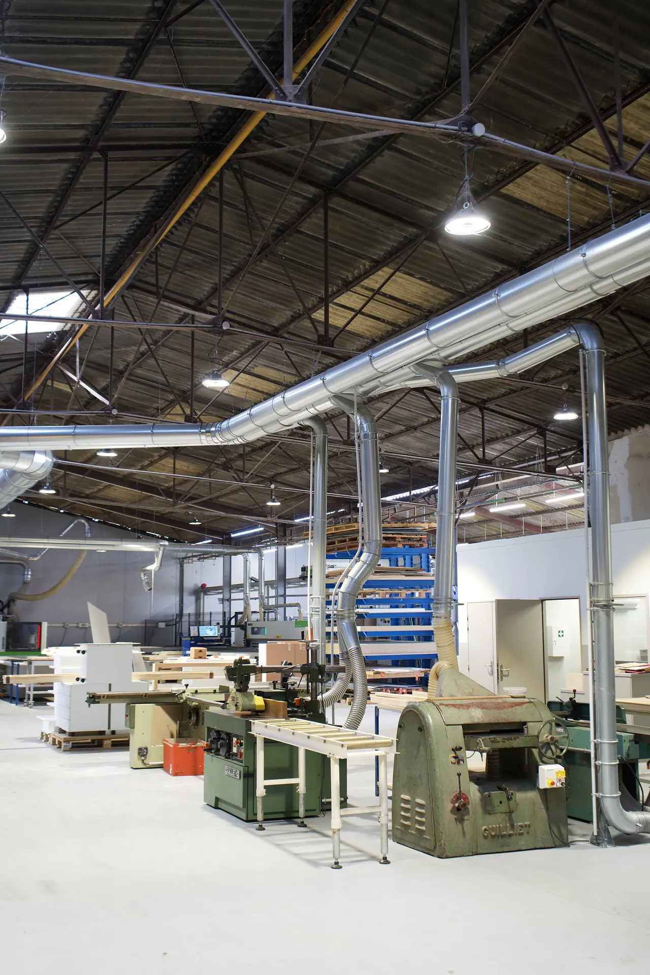 Allée des machines à bois de l'atelier : toupie avec entraîneur et raboteuse reliées à l'aspiration centralisée