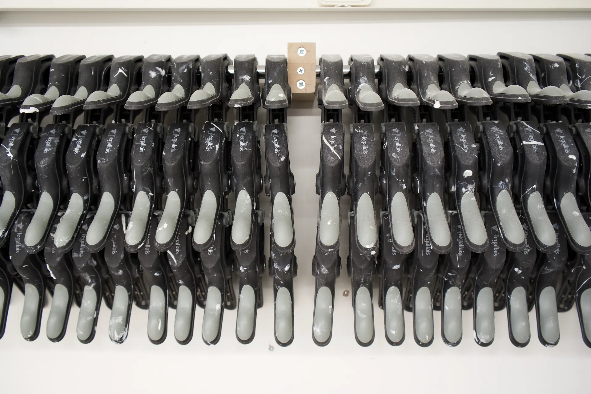 Rangée de serre-joints à serrage rapide suspendus à leur barre, au mur de l'atelier de montage