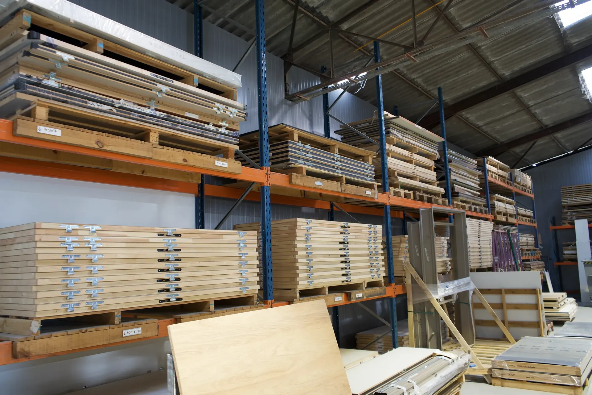 Rayonnages à palettes de l'atelier chargés de panneaux de bois et de panneaux décor sur plusieurs niveaux